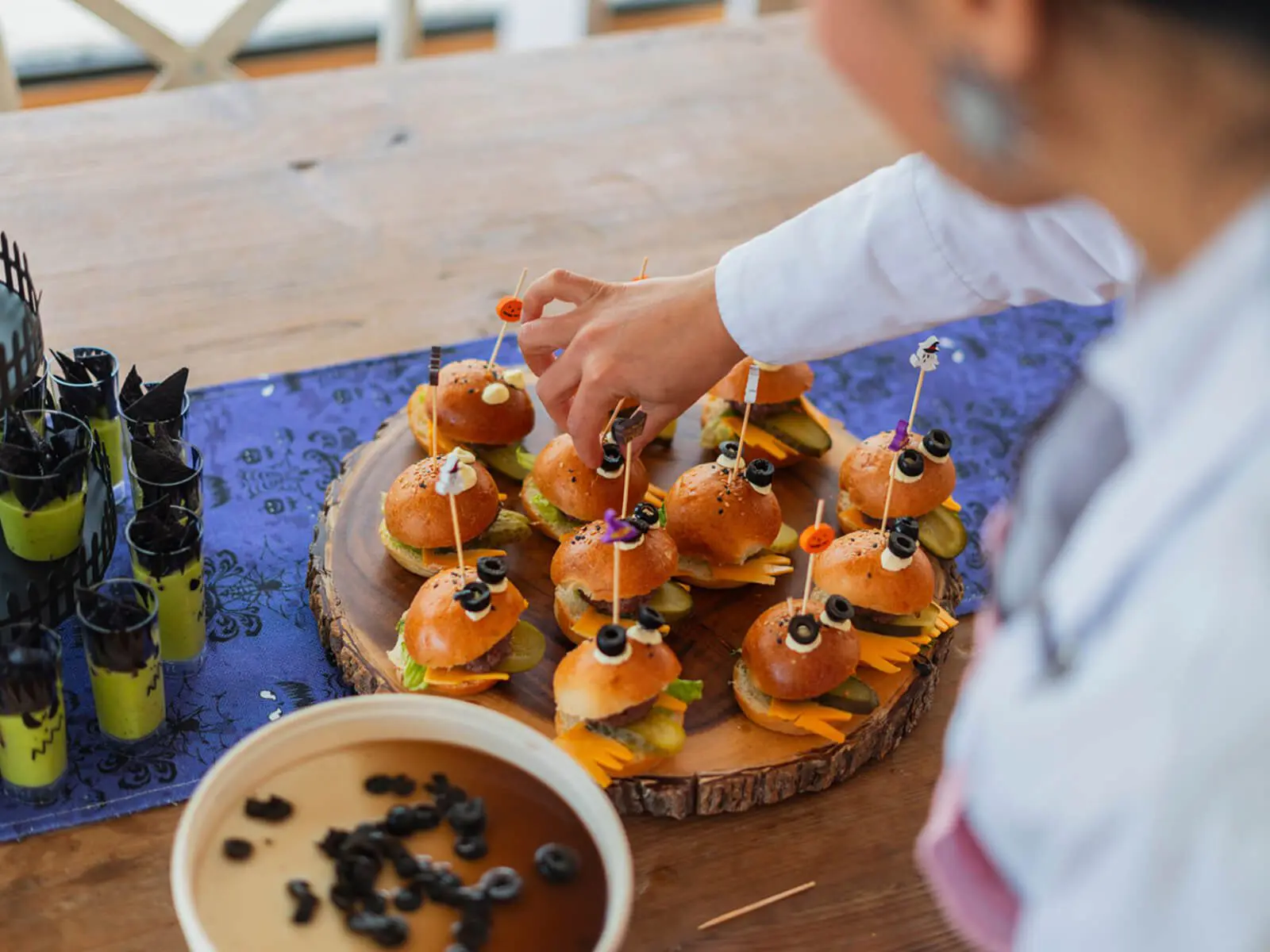 Mini burgers and drinks on wooden tray.