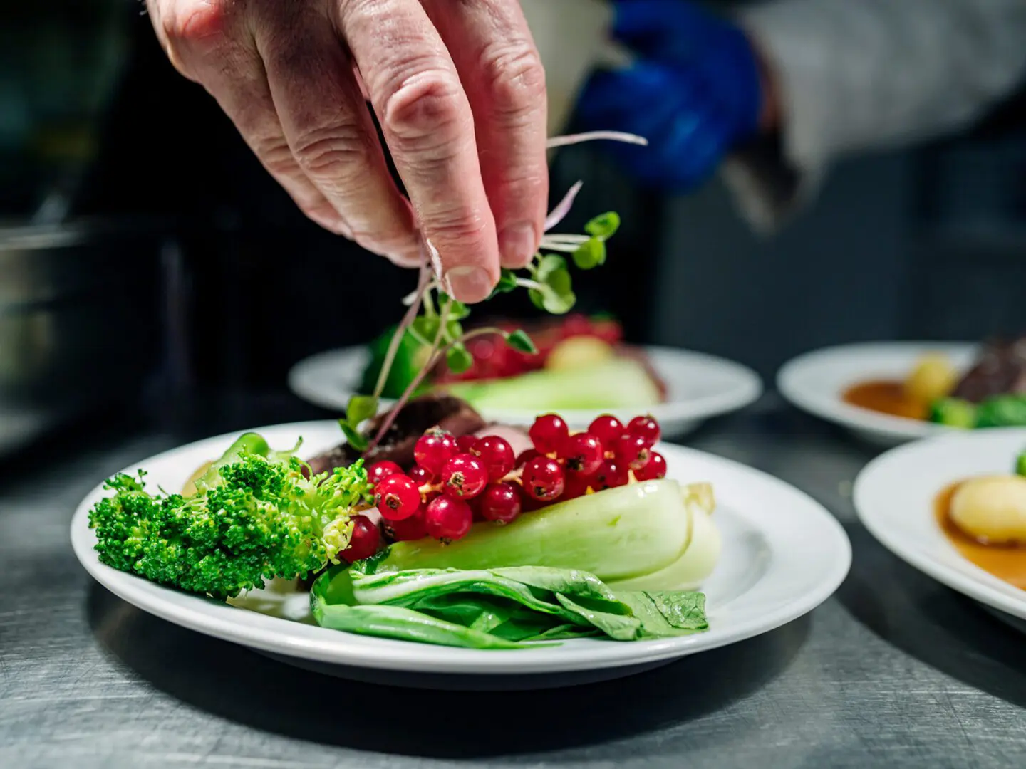 Chef garnishing a dish with greens.