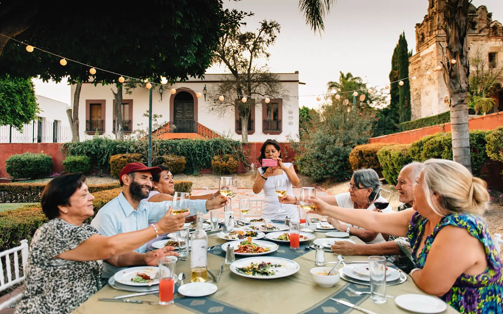 Group toasting at outdoor dinner party.