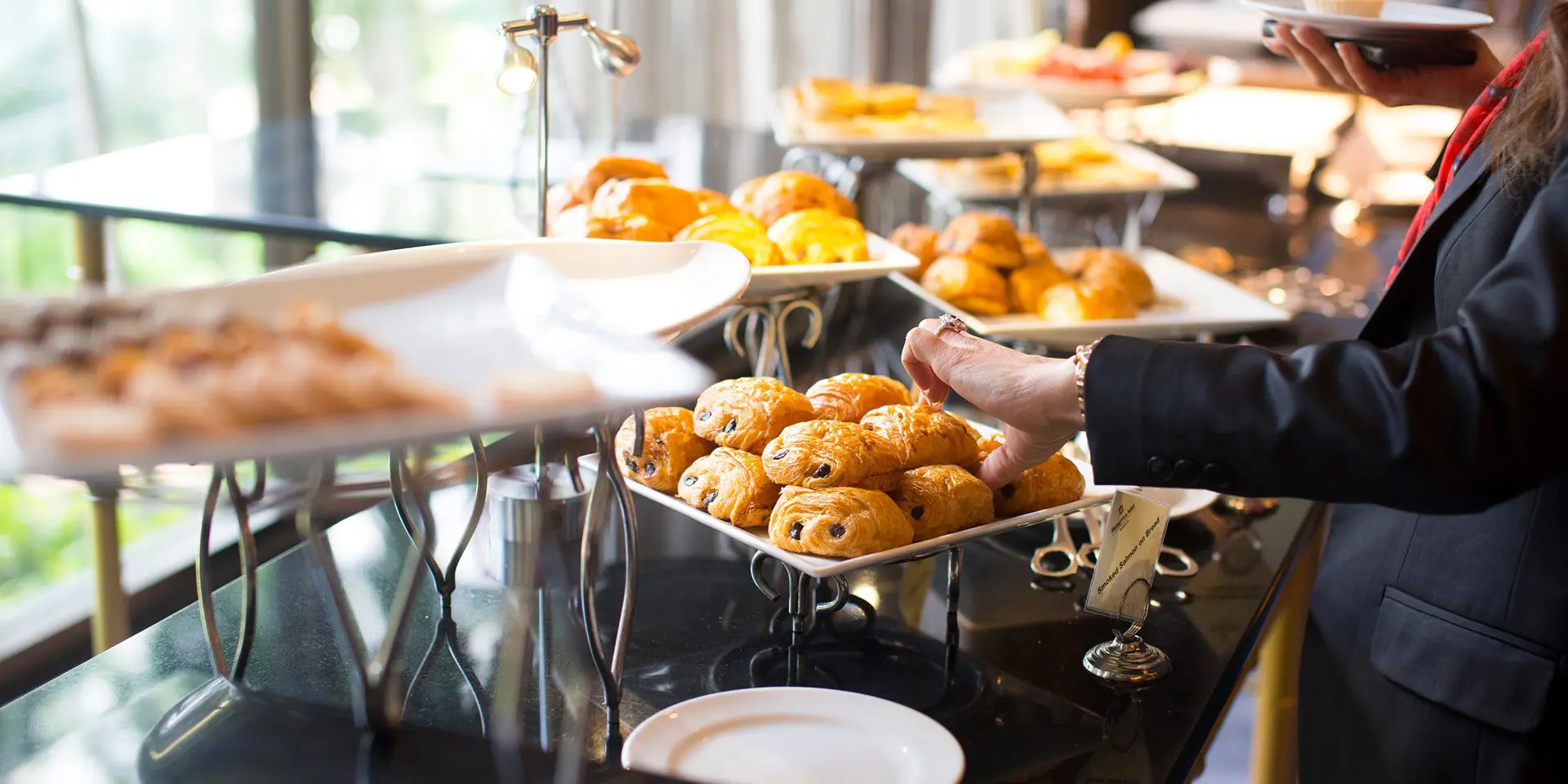 Buffet with pastries and a person serving.