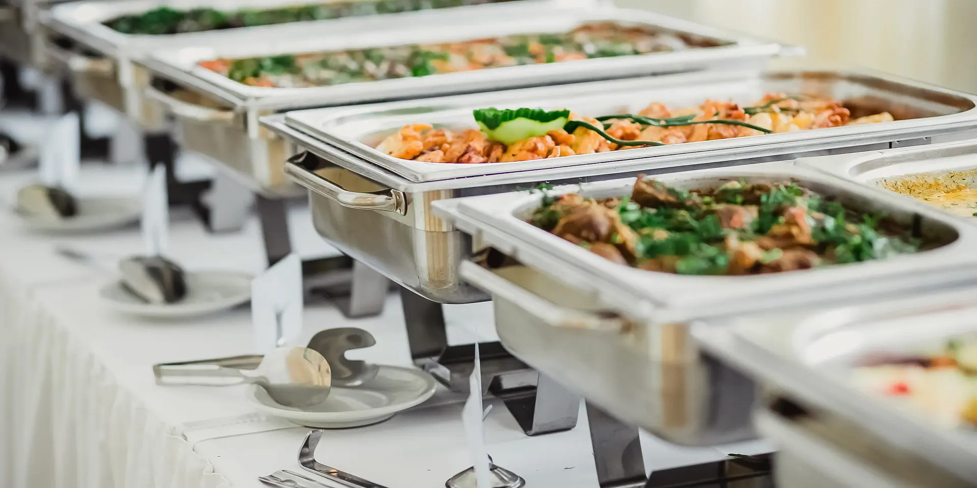 Buffet table with various dishes in trays.