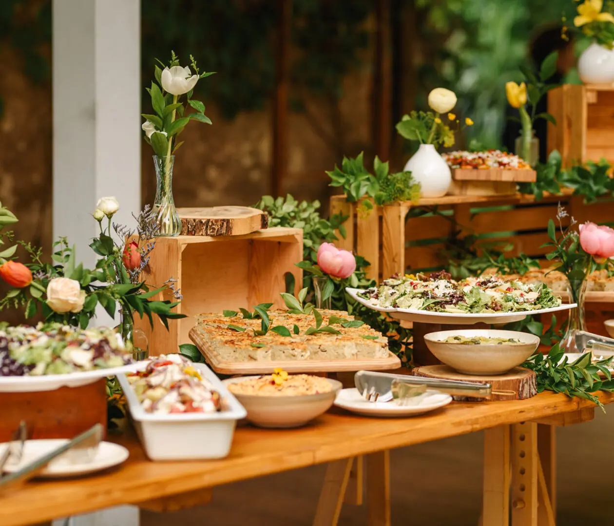 Buffet table with salads and floral decorations.