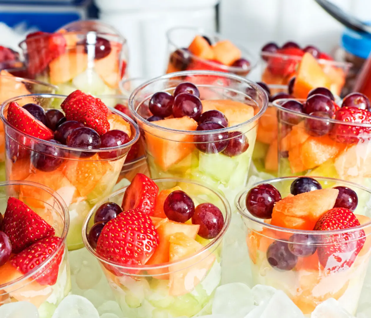 Fruit cups with strawberries, grapes, and melon.